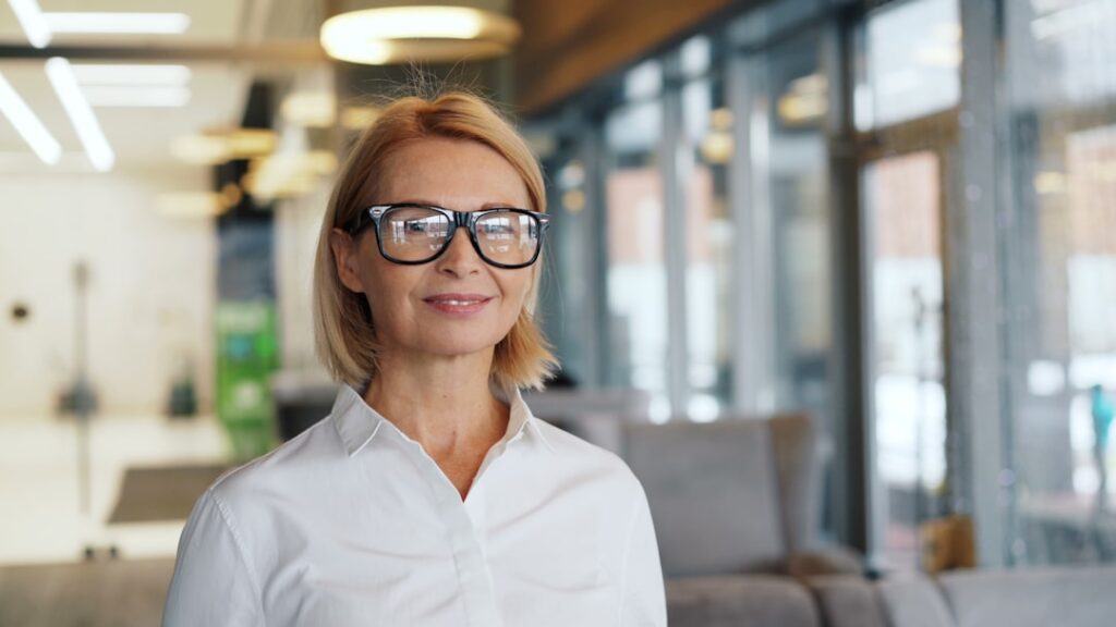a woman wearing glasses standing in front of a couch